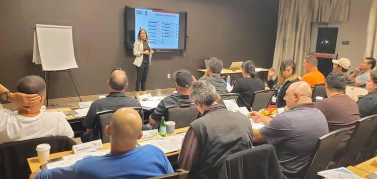 Carolina Marin presenting at an EGOS session, pointing to a chart while attendees follow along at tables